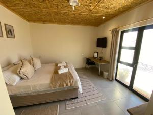 a bedroom with a bed and a desk and a window at Windy Dunes Self -Catering Accommodation, Luderitz in Lüderitz