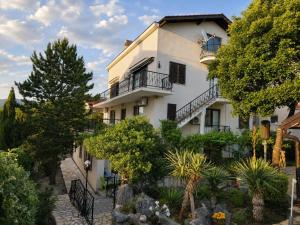 a white building with a balcony and trees at Guest House Dijana in Kraljevica
