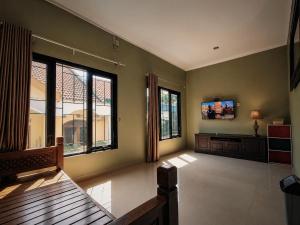 a living room with a tv and some windows at Audi's Homestay near Kotagede in Gondowulung