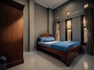 a bedroom with a bed with blue sheets and two windows at Audi's Homestay near Kotagede in Gondowulung