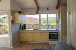 a kitchen with wooden cabinets and a large window at Hvammur 1 with private hot tub in Drangsnes +9 photos