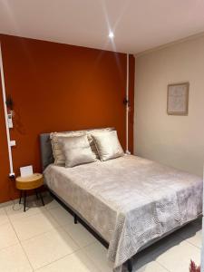 a bedroom with a bed with a orange wall at Résidence les maquis in Koungou