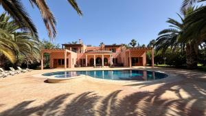 a house with a swimming pool and palm trees at Villa Amazonika By La Siredrah in Segraga
