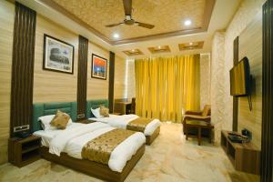 a hotel room with two beds and a television at Hotel Trimurti By Carlton Suites in Ayodhya