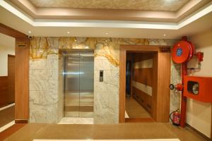 a walk in shower in a bathroom with a stone wall at Hotel Trimurti By Carlton Suites in Ayodhya