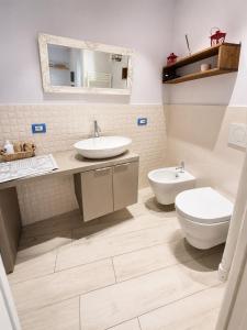 a bathroom with two sinks and a toilet and a mirror at Monolocale Incantevole in Montichiari