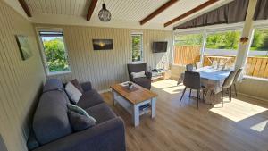a living room with a couch and a table at Hvammur 1 with private hot tub in Drangsnes