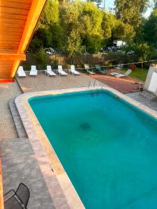 a swimming pool in a yard with lounge chairs and a wooden roof at Pensiunea Selena Bascov-Pitesti in Bascov