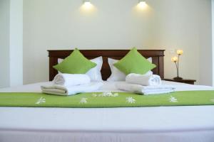 a bed with green and white pillows and towels at Ayurishi Villa in Hikkaduwa