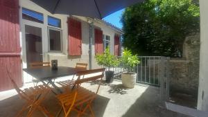 a patio with a table and chairs and an umbrella at Chez Valérie côté Sud in Saint-Jean-du-Gard