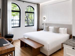 a bedroom with a large white bed and two windows at Casa Lerma in Mexico City