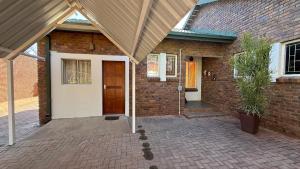 a brick house with a wooden door and a brick wall at The Willows in Polokwane