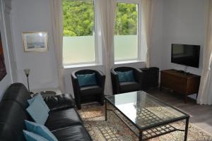 a living room with a couch and two chairs and a tv at Château d'Harnoy in Yvoir