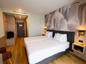 a bedroom with a white bed with a painting on the wall at Mercure Alba Iulia in Alba Iulia +118 photos