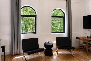 a living room with two chairs and a desk and two windows at Casa Lerma in Mexico City