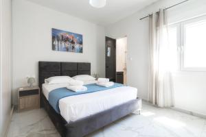 a white bedroom with a large bed with blue sheets at Newly built detached house with parking 2 in Larisa