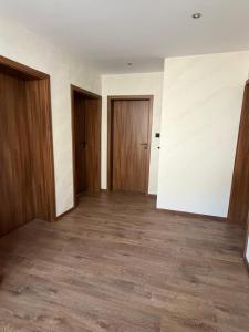 an empty room with two doors and wooden floors at Sunny House in Madzhare