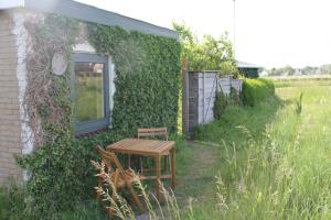 a wooden table and chair next to a building at Onder de regenboog in Egmond aan den Hoef