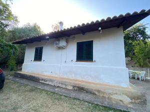 a white house with green shutters on it at Medlar apartments in Zambrone