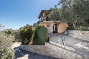 a house on a hill with a stone wall at Skiathos Garden Cottages in Skiathos