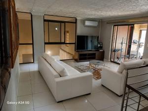 a living room with two white couches and a television at Duco self-catering in Nelspruit
