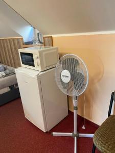 a white fan in a hotel room with a microwave at Penzion Kolovna in Dobrá