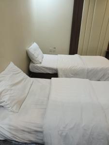 two beds in a hotel room with white sheets at افاق in Khamis Mushayt