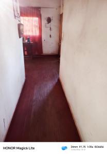 an empty hallway with a hard wood floor and a red door at Narraverrete family in Chillán