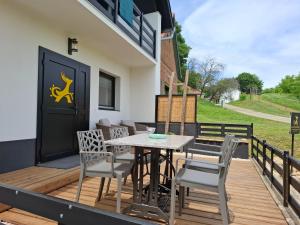 a deck with a table and chairs and a black door at Mecsek Vendégház in Mecseknádasd