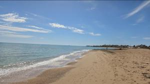 a sandy beach with the ocean on a sunny day at AM-MARE in Villaggio Azzurro