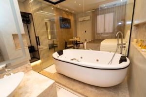 a bathroom with a tub and a sink and a bed at Hotel Capital Das Pedras in Teófilo Otoni