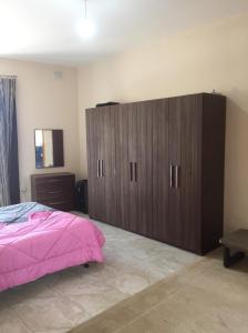 a bedroom with a large wooden cabinet and a pink bed at Quiet and Lovely Residence in St. Julianʼs