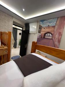 a bedroom with a bed with a painting on the wall at Bab Rmouz apartment in Tétouan