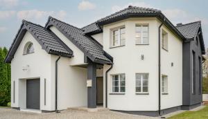a white house with a black roof at Lumy Housing in Pärnu