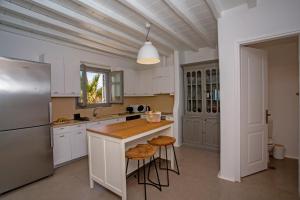 a kitchen with white cabinets and a counter with stools at South Star private Villa in Mikonos