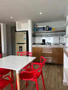 a kitchen with a white table and red chairs at Ventanas al Paraiso Apartment Cancun in Cancún
