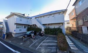 a car parked in a parking lot next to a building at Mason Famile Naruse in Machida
