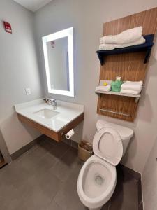 a bathroom with a toilet and a sink and a mirror at Micro Hotel in Conyers