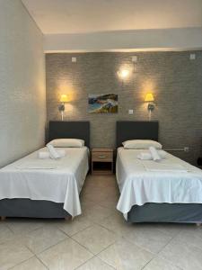 two beds in a hotel room with two lamps at ABEAS Studios 2 in Avlákia