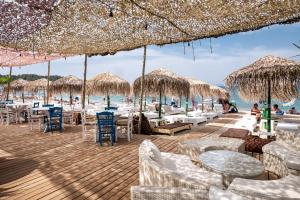 a beach with tables and chairs and straw umbrellas at Piatsa Michalis in Potos