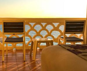 a room with two chairs and a bed and a table at Ventanas al Paraiso Apartment Cancun in Cancún