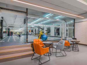 an office with orange chairs and tables and a gym at Mercure Beijing Future Science City in Beijing