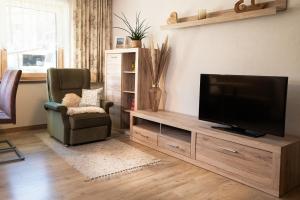 a living room with a flat screen tv and a chair at Ferienwohnung Kreidl in Schlitters