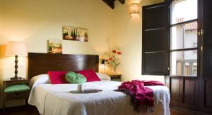 sypialnia z łóżkiem z czerwonymi i zielonymi poduszkami w obiekcie Apartamentos Santillana del Mar w mieście Santillana del Mar