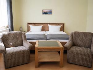 a bedroom with a bed with two chairs and a table at Pension NoAs in Sassnitz