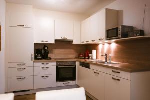a kitchen with white cabinets and a sink at Ferienwohnung Kreidl in Schlitters