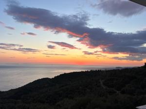 a sunset over the ocean with trees in the foreground at Hotel Piqeras Kris in Piqeras
