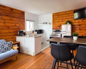 a kitchen and living room with wooden walls and a table at Hunts Point Beach Cottages - Cottage #2 in Summerville Centre
