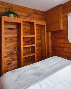 a bedroom with wooden walls and a bed and shelves at Hunts Point Beach Cottages - Cottage #2 in Summerville Centre