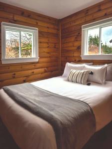 a bedroom with a large white bed with two windows at Hunts Point Beach Cottages - Cottage #2 in Summerville Centre